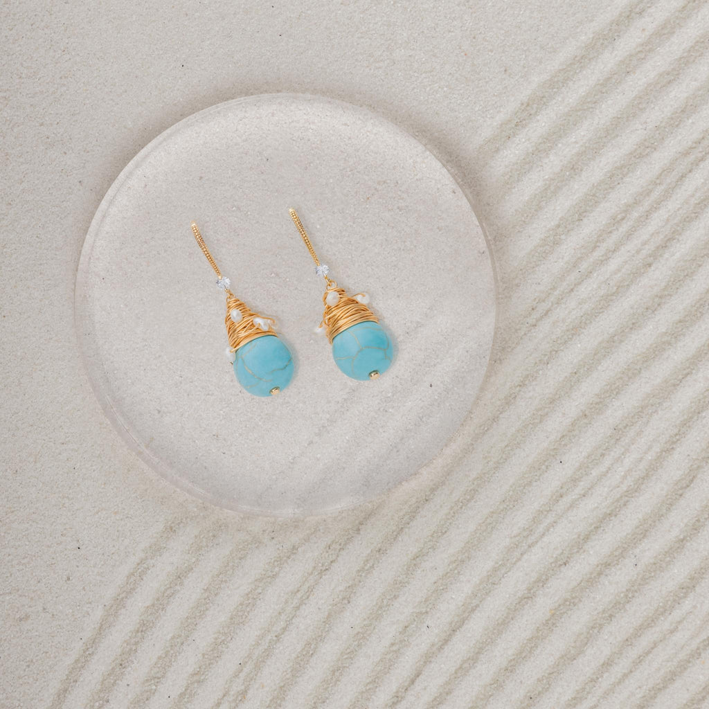 Turquoise Stone Golden Earrings on sand